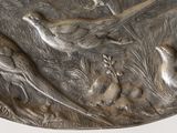 a silver plate with birds on it on a white surface