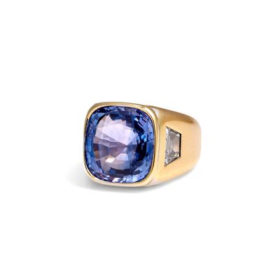gros plan d'une bague avec une pierre bleue et des diamants