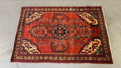 Le tapis posé au sol est rouge et présente un motif de fleurs et de feuilles.