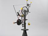 a black and yellow sculpture of a spinning machine on a pedestal