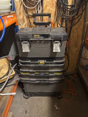 une pile de caisses à outils dans un garage, à côté d'autres outils