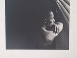 une photo en noir et blanc d'une femme appuyée contre une fenêtre