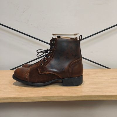 quelqu'un porte une paire de bottes marron posée sur une étagère en bois