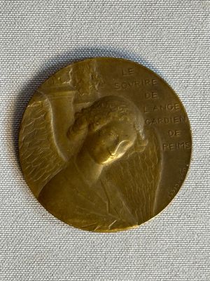 une médaille d'or sur laquelle figure le visage d'une femme, posée sur un tissu blanc