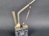 an antique silver metal lighter with blue and white flowers on it