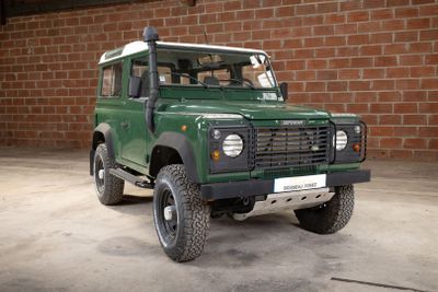 an image of a green land rover parked in front of a brick wall