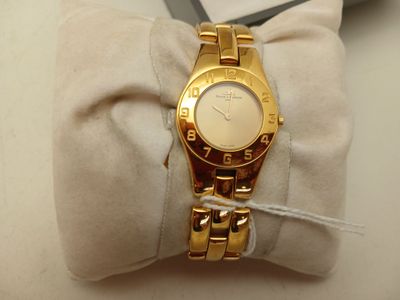 une montre-bracelet en or posée sur un coussin blanc