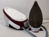 a red and white iron sitting on a table next to a white and black iron