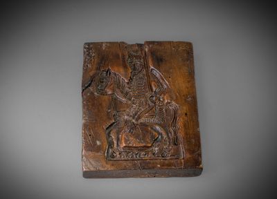 une plaque en bois sculpté représentant un homme à cheval
