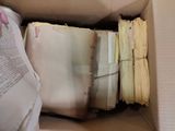a box full of old papers and a hand holding a book