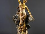 une statue antique en bronze représentant une femme accompagnée d'un chien