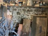 a pile of old wooden chairs in a room with a brick wall