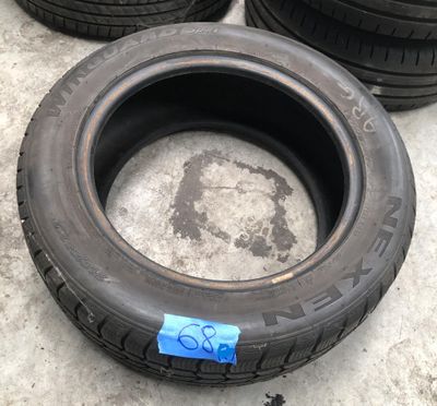 Les pneus sont alignés par terre et portent un autocollant bleu.
