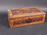 an old wooden box with carvings on it sitting on a black surface