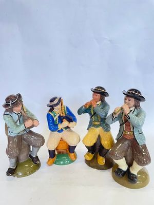 trois figurines représentant des hommes assis sur une surface blanche