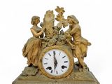 a gold clock with a woman and a child on it