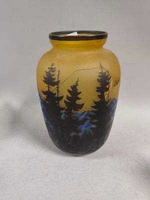 a yellow vase with trees on it sitting on a white surface