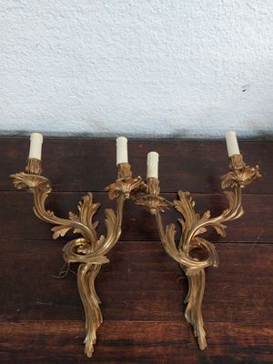 une paire d'appliques murales anciennes en laiton, avec des bougies posées sur une table en bois