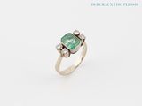 a close up of a ring with a green stone on it