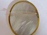 a round mirror with a gold frame on a white wall