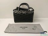 Le sac à main noir se trouve à côté d'un sac gris, sur une table blanche.