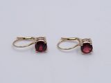 a pair of gold earrings with garnets on them