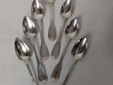 six silver spoons are arranged in a circle on a white surface