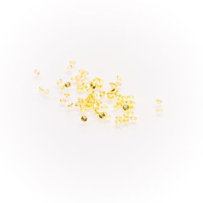 a close up of a pile of yellow beads on a white surface