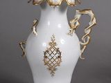 a white vase with gold decoration on it on a gray surface