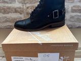 black leather ankle boots with buckles on top of a cardboard box