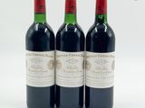 trois bouteilles de vin rouge posées l'une à côté de l'autre sur une surface blanche