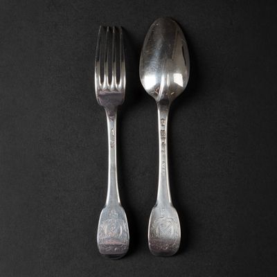two spoons and a fork on a black surface
