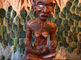 une statue en bois représentant un homme assis sur une table