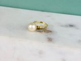 La bague en or avec une perle repose sur une dalle de marbre