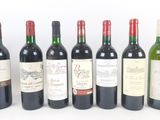 six bottles of wine are lined up in a row on a white surface