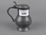 an old pewware pitcher with a spoon on top of it