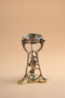 a silver plate with a bird on top of it on a stand