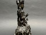 an antique bronze statue of a woman sitting on top of a flower