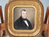 portrait d'un homme en costume noir et nœud papillon, dans un cadre doré
