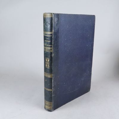 un livre bleu aux bords dorés posé sur une table blanche