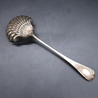 a silver spoon with a leaf shaped handle on a black surface