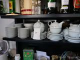 many dishes and cups on a shelf in the kitchen