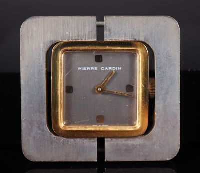 a silver and gold clock sitting on top of a black table