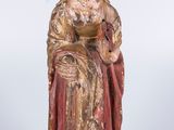 an old statue of a woman in a red dress sitting on a chair