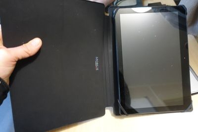 a person holding a tablet and a book on a table
