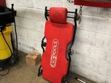 a red chair sitting in a garage next to a yellow trash can