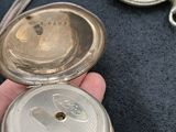 a person holding a silver pocket watch in their hand
