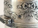 a silver plate with a lid that has a flower design on it