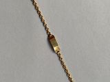 gros plan d'un bracelet en or sur une surface blanche