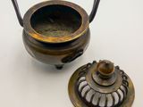 an old metal pot and a small metal bowl on a white surface
